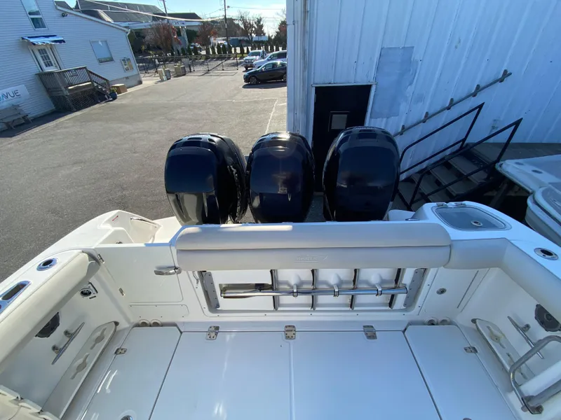 Slide: The Image of 2017 Boston Whaler 350 Outrage boat with triple outboard engines, docked near a building. - 13