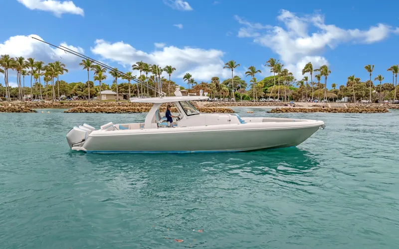 Slide: The Image of 2020 Intrepid 407 Panacea boat cruising on clear blue water with palm trees in the background. - 2