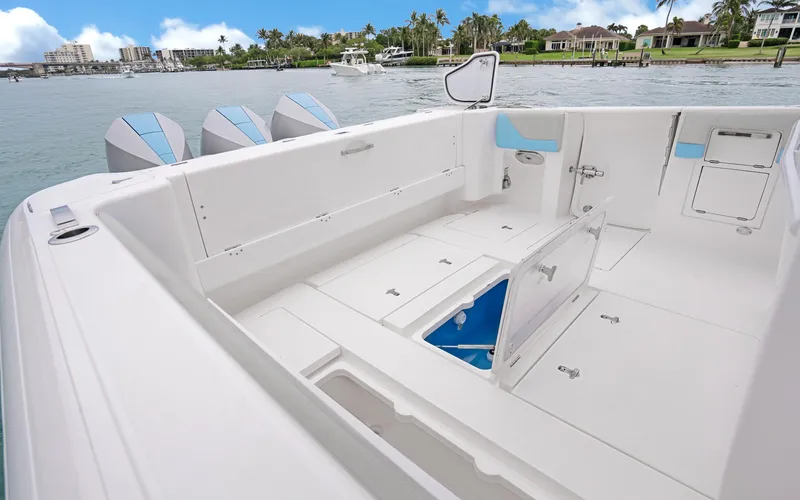 Slide: The Image of 2020 Intrepid 407 Panacea boat interior with open storage compartments, docked by a scenic waterfront. - 27