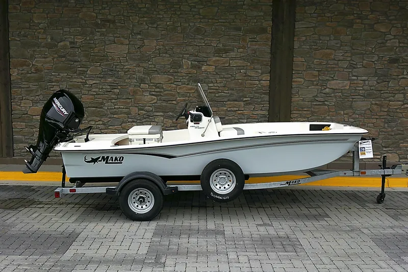 The Image of 2025 Mako Pro Skiff 15 CC boat on trailer, parked against stone wall. - 0