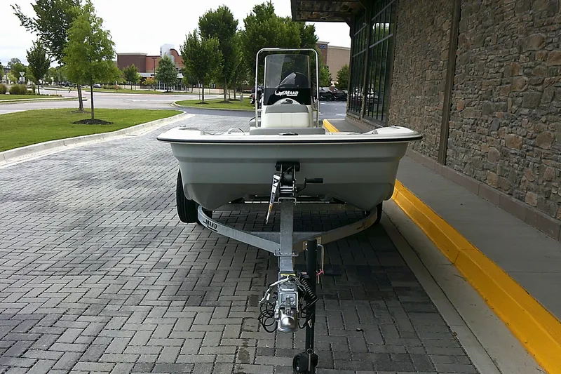 Slide: The Image of 2025 Mako Pro Skiff 15 CC boat on trailer, parked on paved driveway. - 2