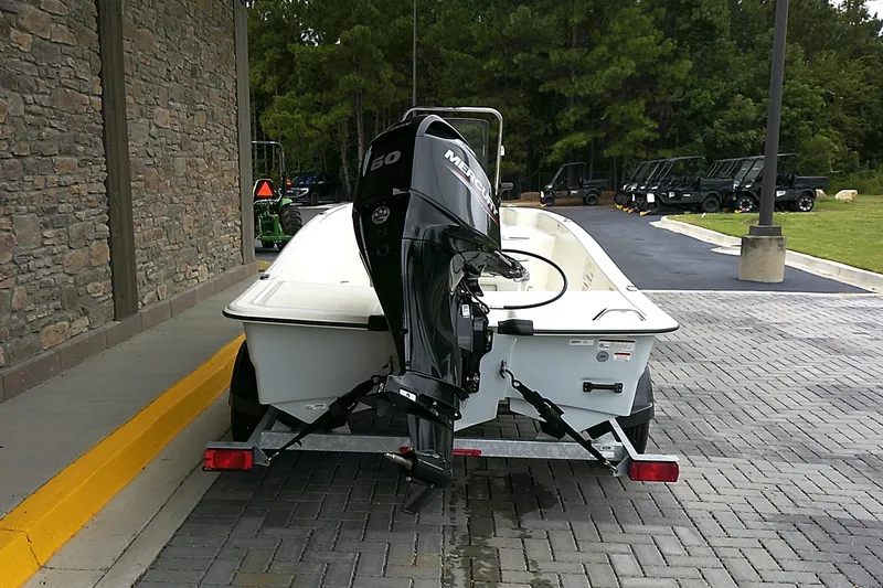 Slide: The Image of 2025 Mako Pro Skiff 15 CC boat on trailer, parked near stone wall. - 3