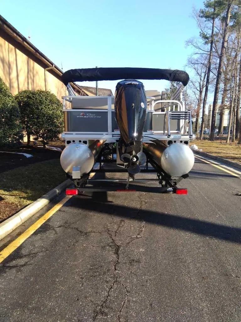 Slide: The Image of 2025 Sun Tracker Party Barge 18 DLX pontoon boat parked on a sunny street. - 3