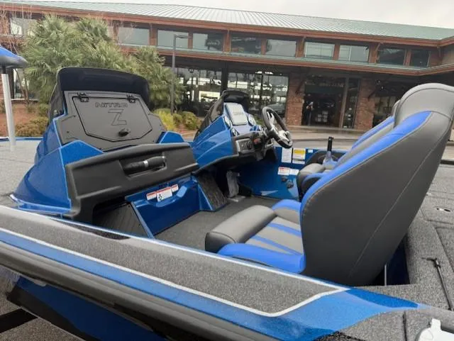 Slide: The Image of 2025 Nitro Z20 XL Pro boat interior with blue and gray seating, parked near a building. - 4