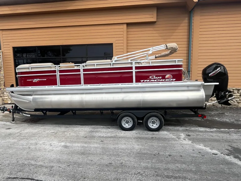 The Image of 2025 Sun Tracker Party Barge 22 RF XP3 pontoon boat on trailer, parked outdoors. - 0