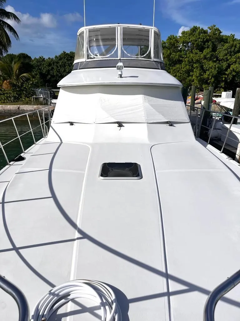 Slide: The Image of 1998 Navigator 53 yacht with sleek white deck, docked near lush greenery. - 1
