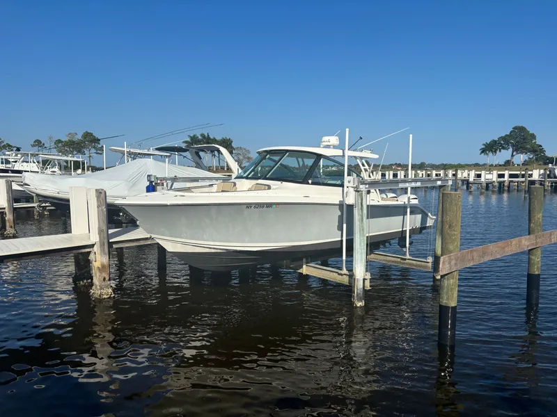 The Image of 2020 Pursuit DC 295 Dual Console boat docked at marina under clear blue sky. - 0
