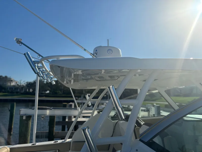 Slide: The Image of 2020 Pursuit DC 295 Dual Console boat with fishing rod holders, docked under clear sky. - 11