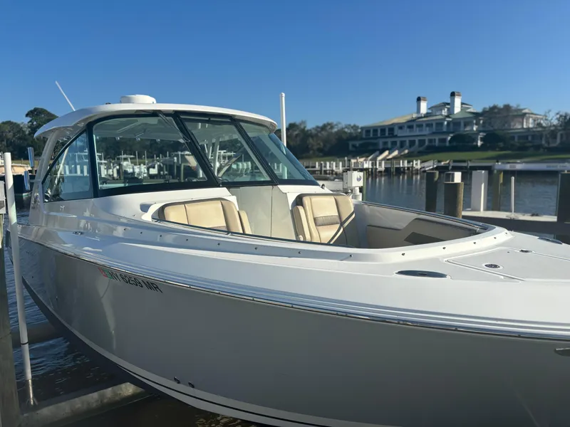 Slide: The Image of 2020 Pursuit DC 295 Dual Console boat docked at marina under clear blue sky. - 3
