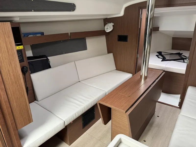 Slide: The Image of 2024 Beneteau Oceanis 34.1 interior with white seating and wood accents. - 4