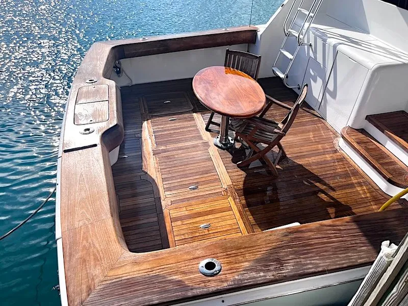 Slide: The Image of 1999 Viking Boats Convertible with wooden deck, table, and chairs on calm water. - 23