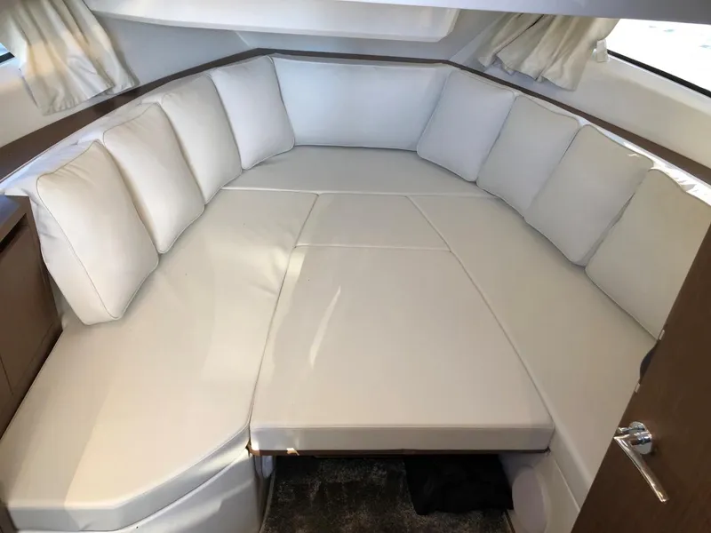 Slide: The Image of 2024 Jeanneau Leader 12.5 WA cabin interior with plush white seating. - 24