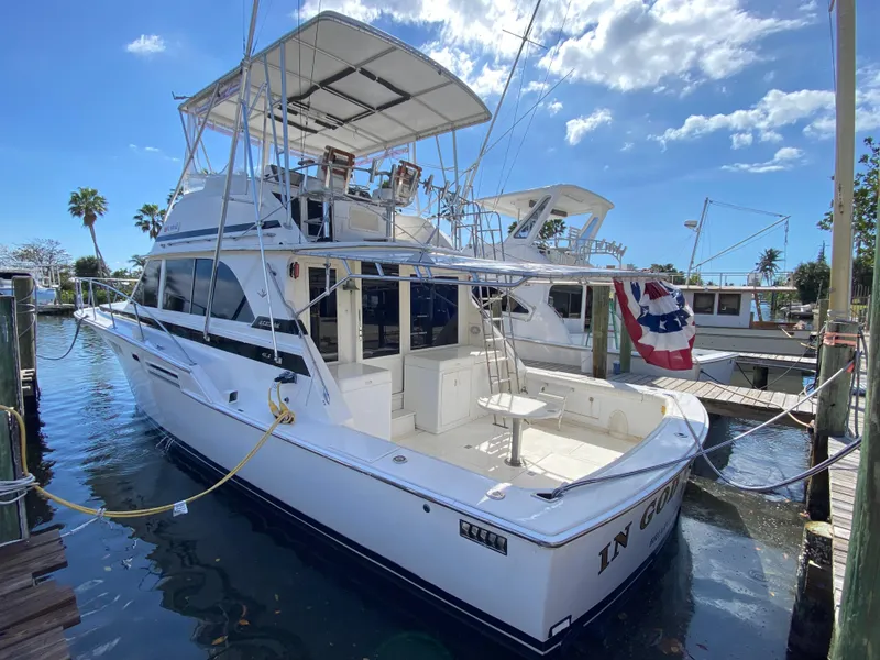 The Image of 1982 Bertram 46.6 War Wagon yacht docked, featuring spacious deck and flybridge under clear skies. - 0