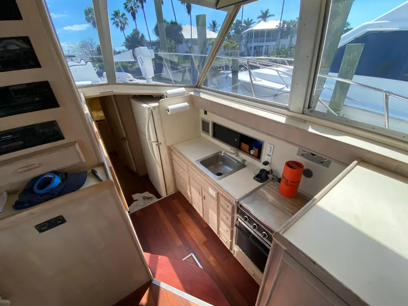Slide: The Image of 1982 Bertram 46.6 War Wagon yacht interior with kitchen, wooden flooring, and large windows. - 23