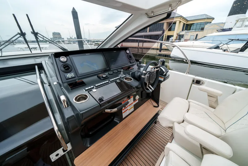 Slide: The Image of 2024 Jeanneau DB/43 OB helm with modern controls and luxurious seating at a marina. - 33