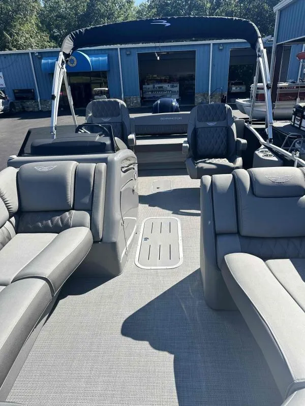 Slide: The Image of 2024 Bennington 23RSB boat interior with gray seating and canopy, parked at a marina. - 12