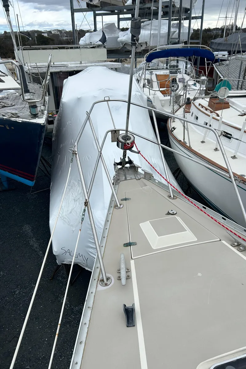 Slide: The Image of 1983 O'Day 39 sailboat docked, covered in white tarp, surrounded by other boats. - 23