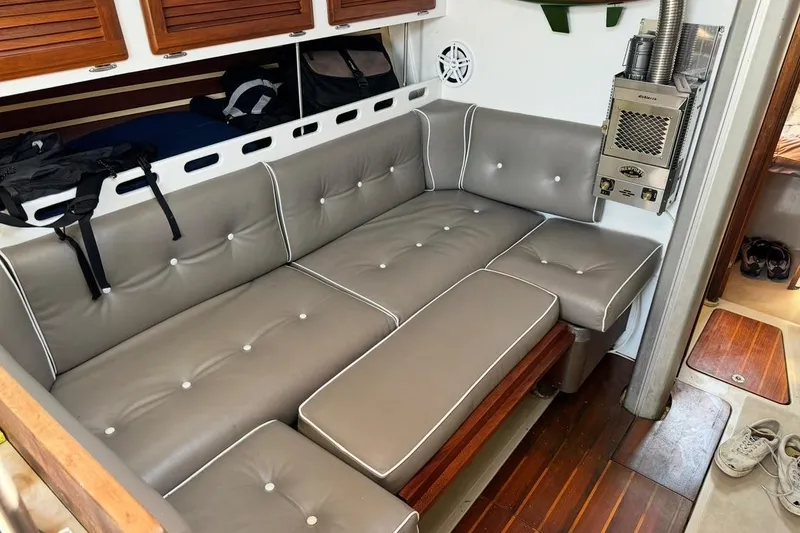 Slide: The Image of 1983 O'Day 39 yacht interior with gray cushioned seating and wooden flooring. - 26