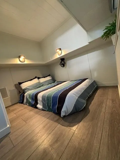 Slide: The Image of Cozy bedroom in 1999 Horizon Stoke House with striped bedding and wooden flooring. - 25