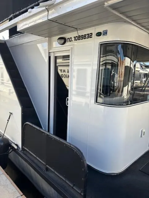 Slide: The Image of 1999 Horizon Stoke Houseboat, sleek white exterior, docked at marina. - 5