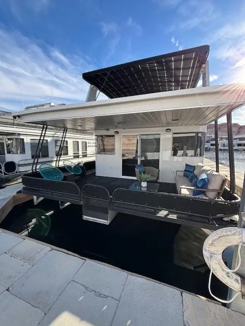 Slide: The Image of 1999 Horizon Stoke Houseboat with outdoor seating, docked under a sunny sky. - 6