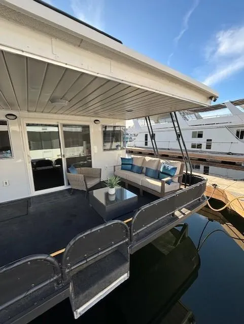 Slide: The Image of 1999 Horizon Stoke Houseboat with outdoor seating, docked at marina under clear sky. - 7
