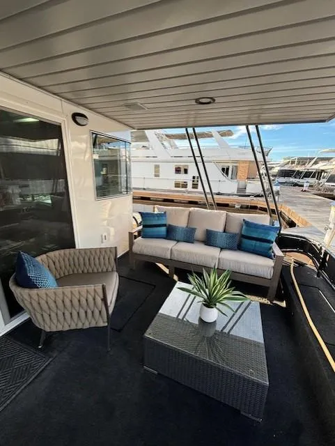 Slide: The Image of 1999 Horizon Stoke House boat deck with modern seating and table, featuring blue accent pillows. - 8