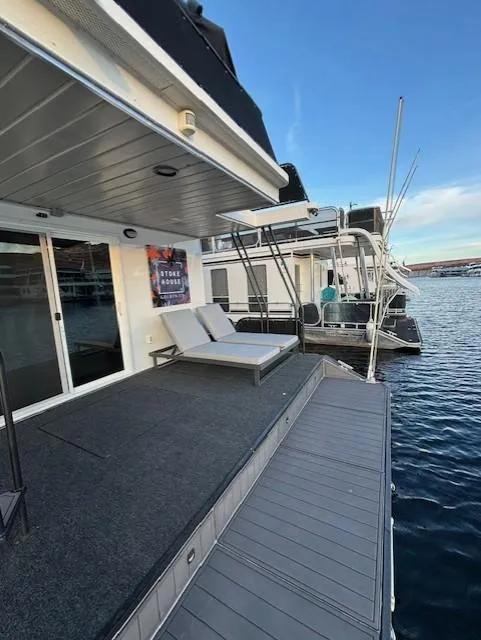 Slide: The Image of 1999 Horizon Stoke Houseboat with deck, lounge chairs, and water view. - 9