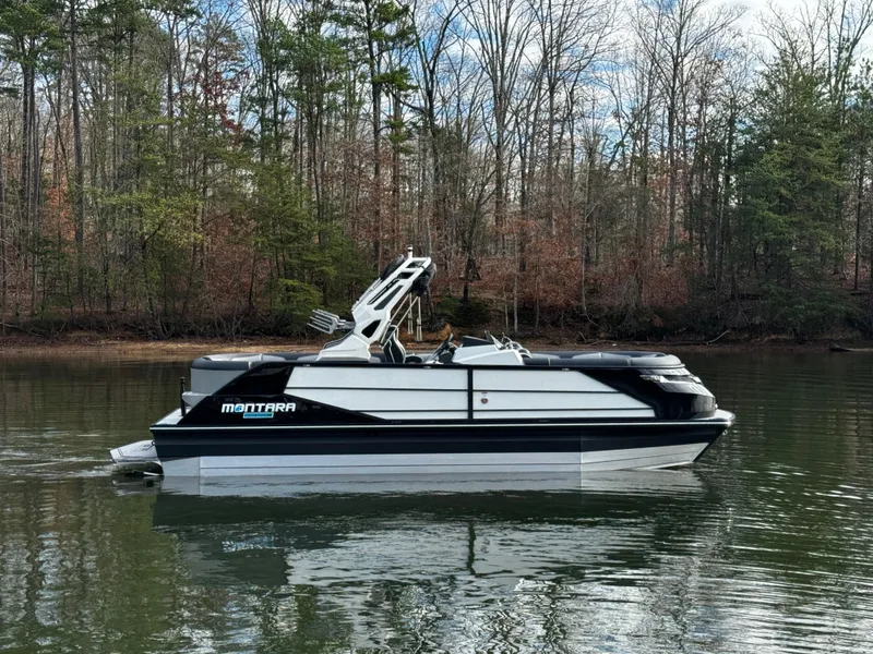 Slide: The Image of 2025 Montara Surf Boss 2.0 25 boat on a calm lake with forested background. - 11