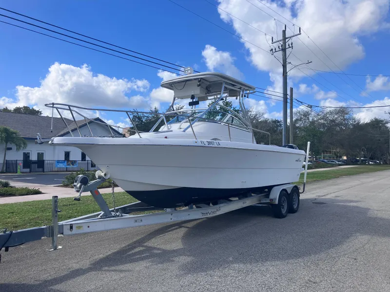 Slide: The Image of 1998 Pro-Line 241 Walkaround boat on trailer, parked on a suburban street. - 1