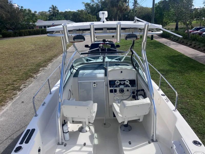 Slide: The Image of 1998 Pro-Line 241 Walkaround boat with dual seats and steering console, parked on grass. - 11