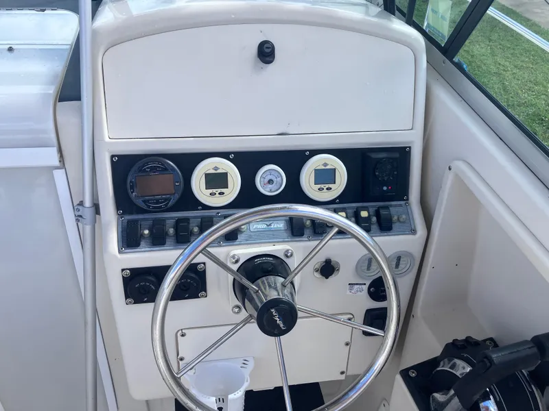 Slide: The Image of 1998 Pro-Line 241 Walkaround boat dashboard with steering wheel and gauges. - 17