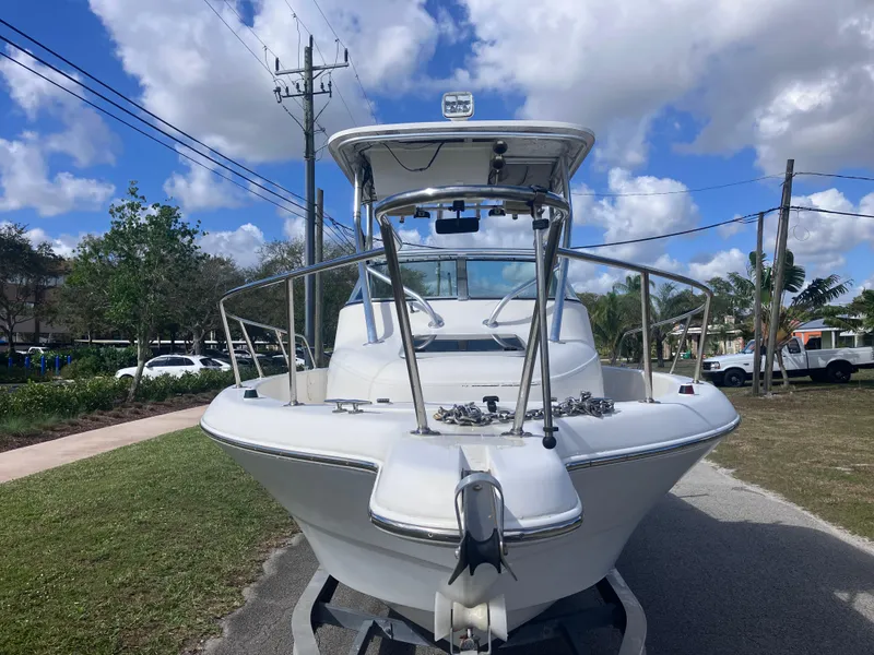 Slide: The Image of 1998 Pro-Line 241 Walkaround boat on trailer, parked outdoors under a partly cloudy sky. - 2