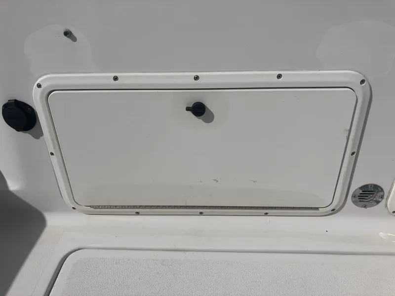 Slide: The Image of 1998 Pro-Line 241 Walkaround boat storage compartment with latch, white exterior. - 25