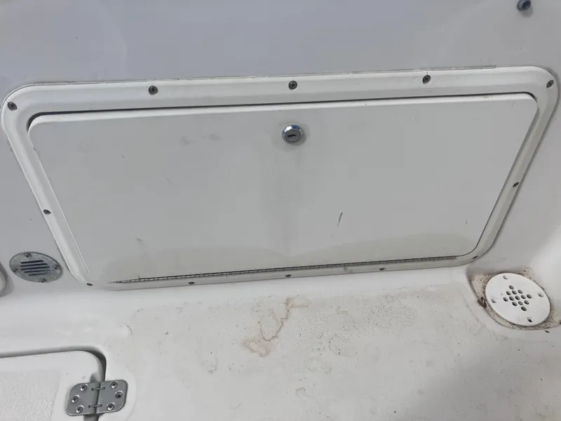 Slide: The Image of 1998 Pro-Line 241 Walkaround boat storage compartment with latch and drainage feature. - 26