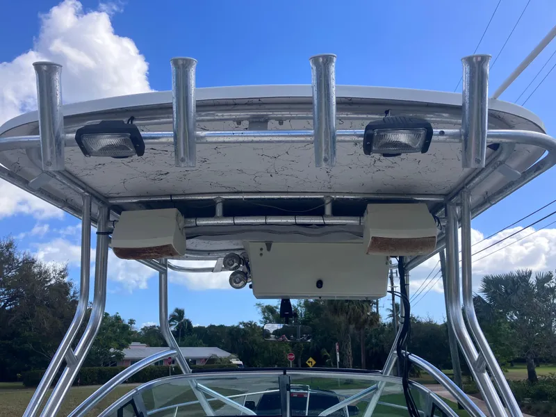 Slide: The Image of 1998 Pro-Line 241 Walkaround boat with T-top and rod holders under a clear blue sky. - 28