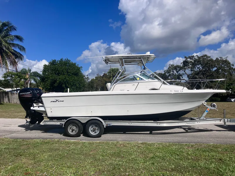 Slide: The Image of 1998 Pro-Line 241 Walkaround boat on trailer, parked outdoors under a blue sky. - 4