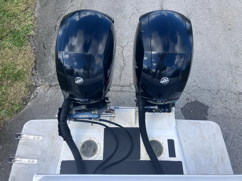 Slide: The Image of 1998 Pro-Line 241 Walkaround boat with dual outboard motors on a paved surface. - 45