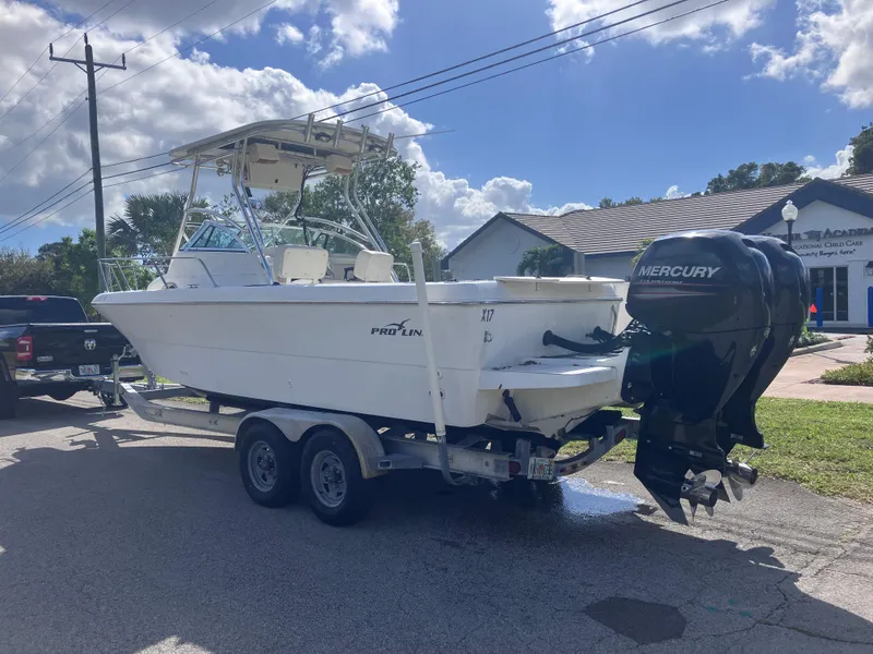 Slide: The Image of 1998 Pro-Line 241 Walkaround boat on trailer with Mercury outboard motor, parked outdoors. - 7