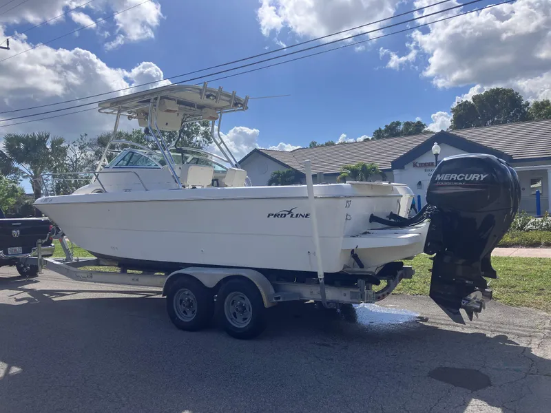 Slide: The Image of 1998 Pro-Line 241 Walkaround boat on trailer with Mercury outboard motor, parked outdoors. - 8