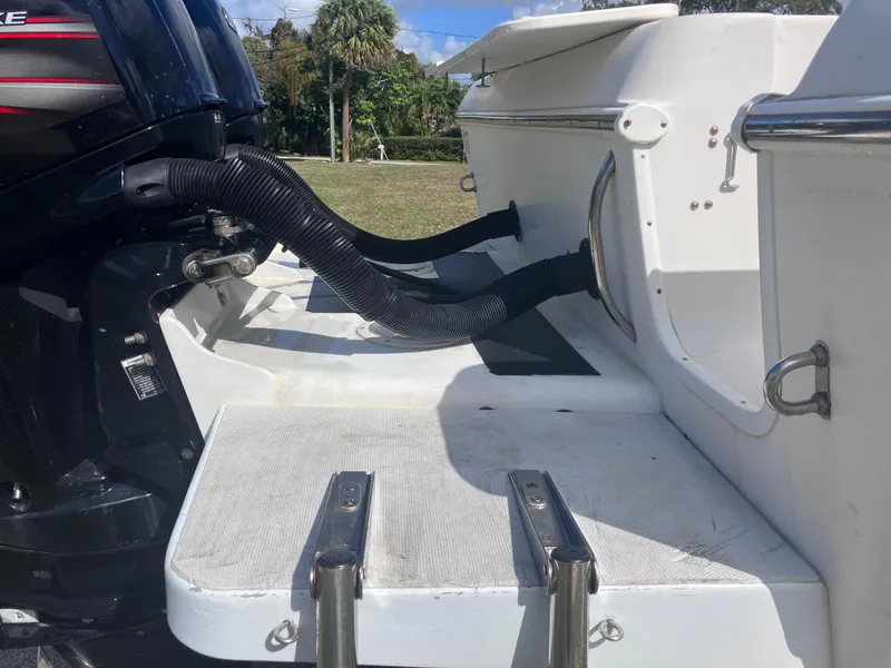 Slide: The Image of 1998 Pro-Line 241 Walkaround boat stern with motor and ladder, outdoor setting. - 9
