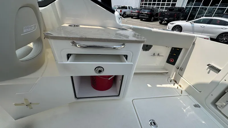 Slide: The Image of 2025 Boston Whaler 240 Vantage boat interior with storage compartment and red bucket. - 12