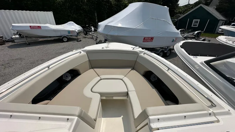 Slide: The Image of 2025 Boston Whaler 240 Vantage boat interior with cushioned seating, parked outdoors. - 33