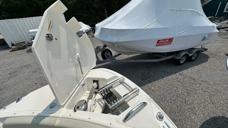 Slide: The Image of 2025 Boston Whaler 240 Vantage boat with open storage compartment, parked on gravel. - 35