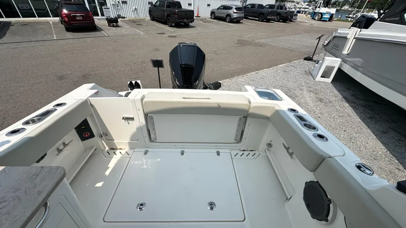 Slide: The Image of 2025 Boston Whaler 240 Vantage boat interior with seating and storage, parked outdoors. - 7