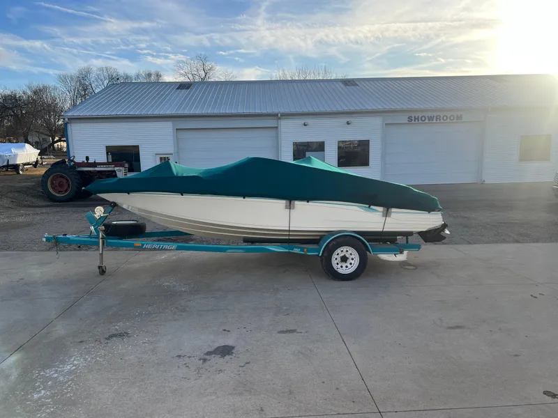 Slide: The Image of 1992 Celebrity 180 Bowrider boat on trailer, covered, parked outside a showroom. - 21