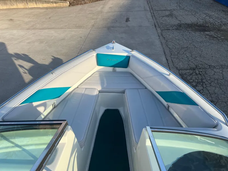 Slide: The Image of 1992 Celebrity 180 Bowrider boat with white and teal interior, docked on concrete. - 9