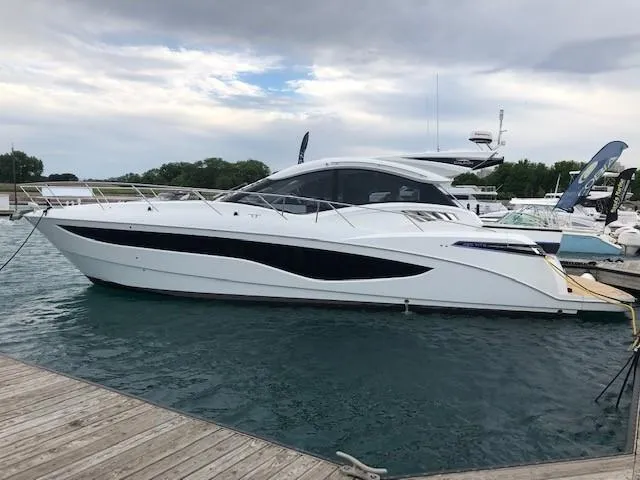 Slide: The Image of 2018 Galeon 485 yacht docked on a calm marina under a cloudy sky. - 2