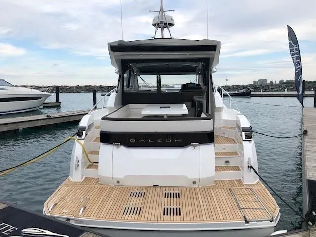 Slide: The Image of Galeon 485 yacht, 2018 model, docked at a marina with wooden deck. - 5
