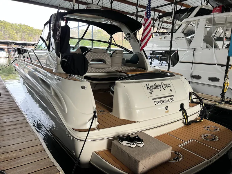Slide: The Image of 2002 Sea Ray 380 Sundancer docked, featuring spacious deck and American flag. - 26